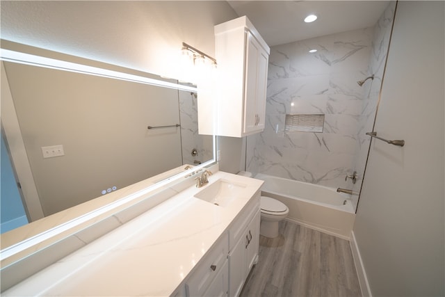 full bathroom featuring hardwood / wood-style flooring, tiled shower / bath combo, toilet, and vanity