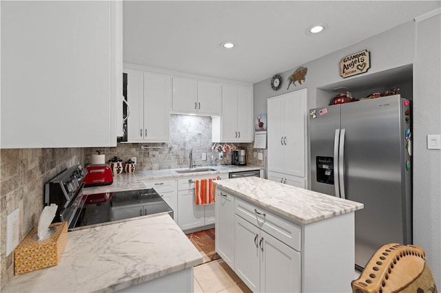 kitchen with sink, white cabinetry, backsplash, stainless steel appliances, and a center island