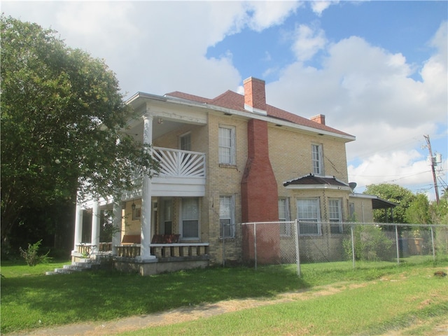 back of property featuring a lawn, a balcony, and covered porch