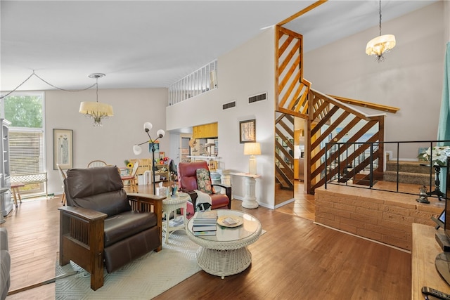 living room featuring high vaulted ceiling, light wood-type flooring, and an inviting chandelier