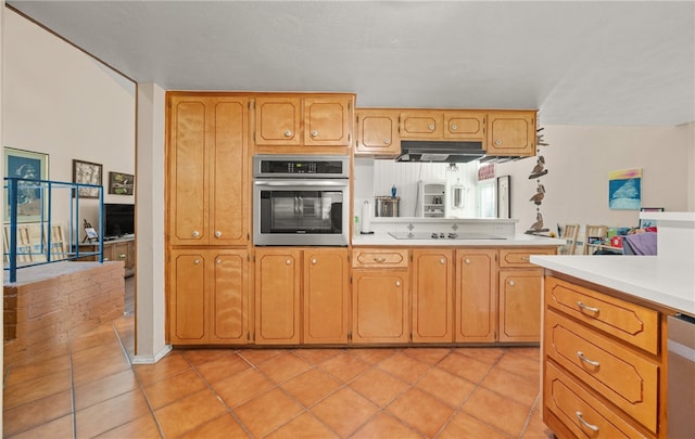 6845 Aswan Dr, Corpus Christi, TX 78412 - kitchen featuring stainless steel appliances, light countertops, light tile patterned floors, under cabinet range hood, and brown cabinets