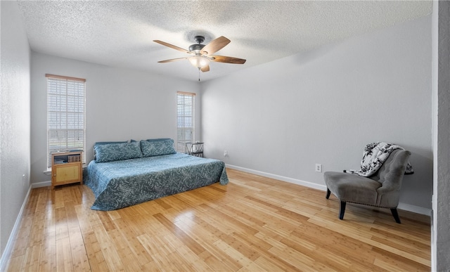 bedroom with hardwood / wood-style flooring, ceiling fan, and a textured ceiling