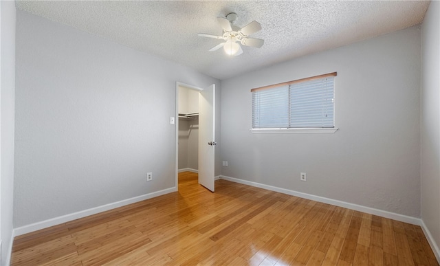 empty room with ceiling fan, a textured ceiling, and light wood-type flooring