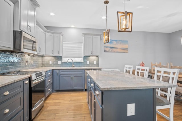 112 Dolphin Ct, Aransas Pass, TX 78336 - kitchen featuring appliances with stainless steel finishes, light wood-style floors, a kitchen island, backsplash, and a breakfast bar area