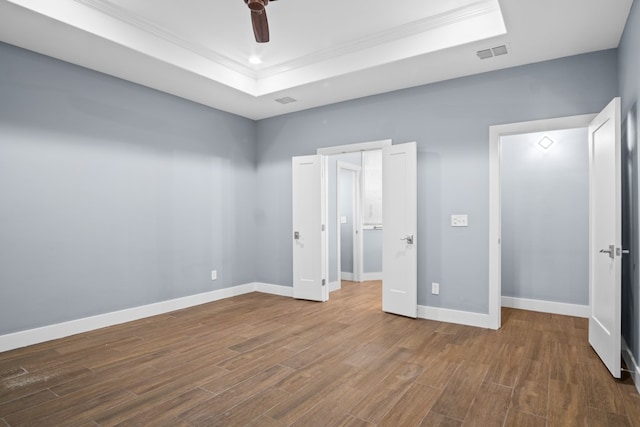 unfurnished bedroom featuring hardwood / wood-style flooring, ceiling fan, and a raised ceiling