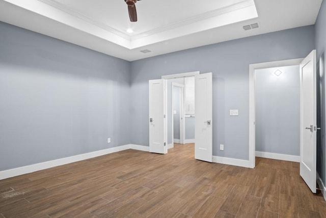 112 Dolphin Ct, Aransas Pass, TX 78336 - unfurnished bedroom with a tray ceiling, ornamental molding, wood finished floors, a ceiling fan, and baseboards