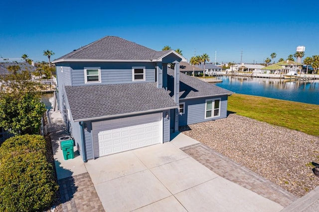 112 Dolphin Ct, Aransas Pass, TX 78336 - traditional-style home featuring concrete driveway, roof with shingles, a water view, a garage, and a front lawn