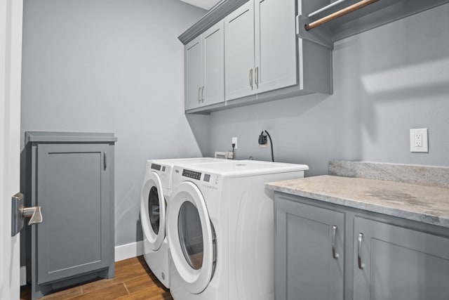 laundry room with dark wood-type flooring, washing machine and dryer, and cabinets