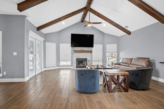 living room with hardwood / wood-style floors, a stone fireplace, beam ceiling, and high vaulted ceiling