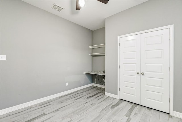 interior space featuring light wood-style floors, baseboards, visible vents, and a ceiling fan