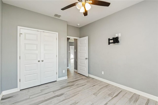 unfurnished bedroom featuring light wood-type flooring, a closet, visible vents, and baseboards