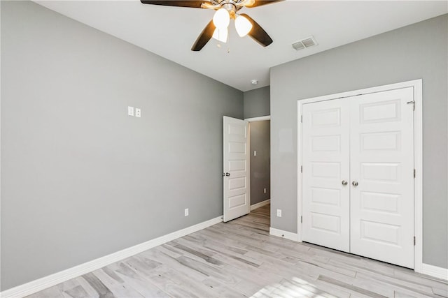 unfurnished bedroom with ceiling fan, light wood-style flooring, visible vents, baseboards, and a closet