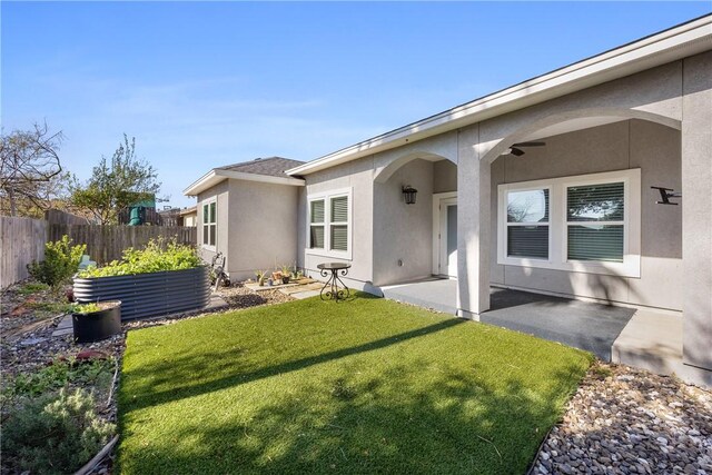 back of property with a lawn, fence, a patio, and stucco siding