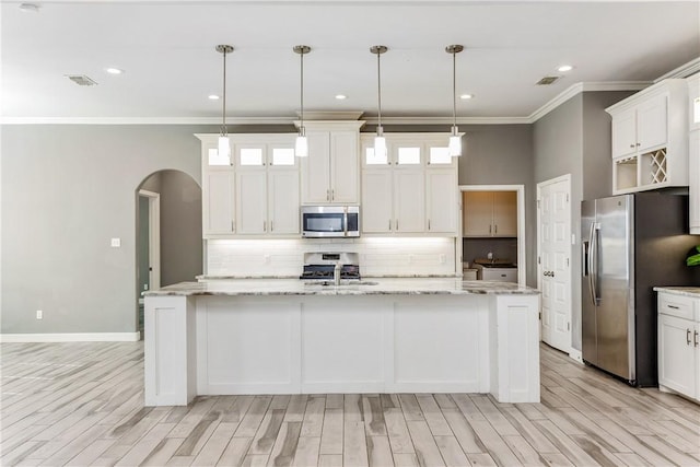 kitchen featuring an island with sink, stainless steel appliances, and decorative light fixtures