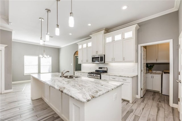 kitchen featuring a kitchen island with sink, appliances with stainless steel finishes, glass insert cabinets, and white cabinets