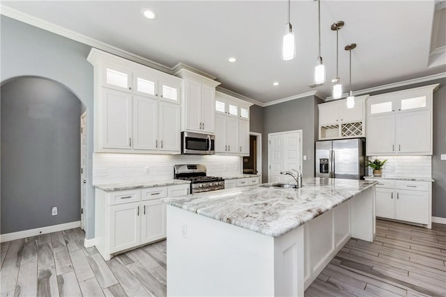 kitchen featuring appliances with stainless steel finishes, a kitchen island with sink, glass insert cabinets, and white cabinetry