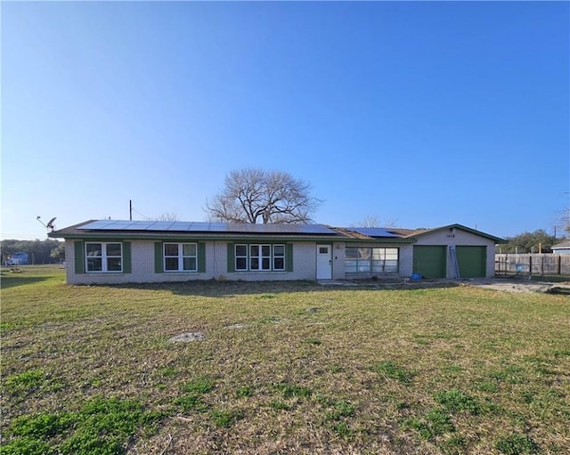 view of front of property featuring solar panels, concrete driveway, a front yard, fence, and a garage