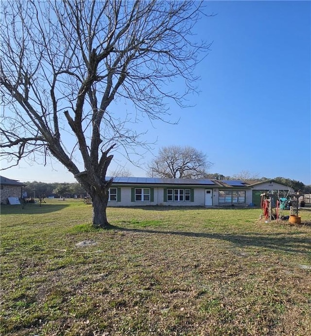 view of front facade featuring solar panels and a front lawn
