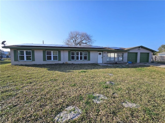 ranch-style house featuring a front lawn, concrete driveway, an attached garage, and solar panels