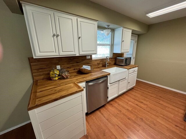 kitchen featuring wood counters, stainless steel appliances, a sink, and white cabinetry