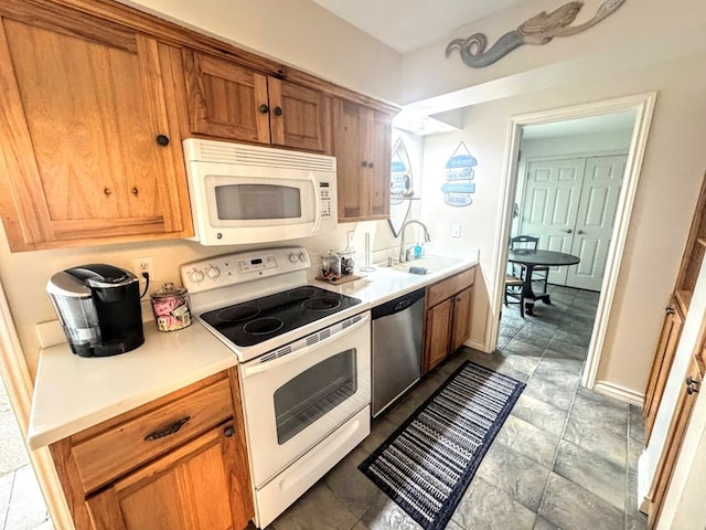 kitchen with white appliances, baseboards, brown cabinets, light countertops, and a sink