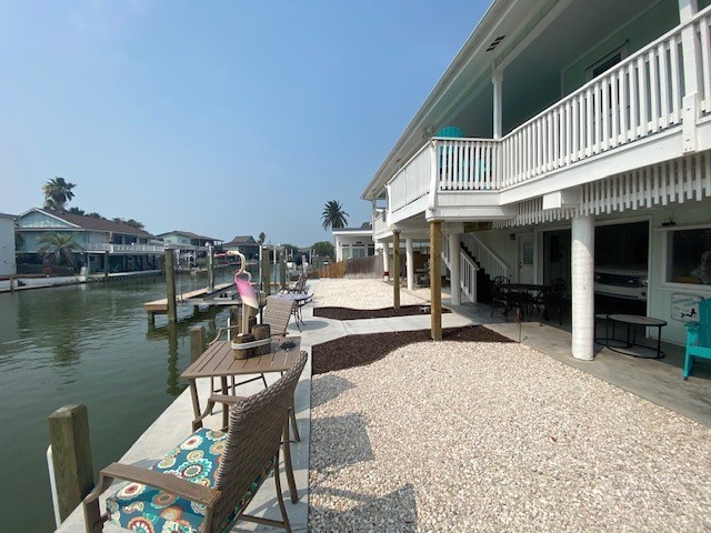 dock area featuring a patio area, a water view, and stairway