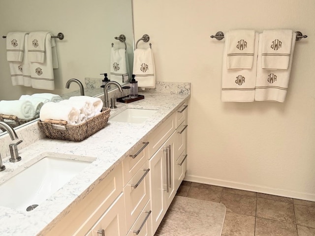 full bath with tile patterned flooring, a sink, baseboards, and double vanity