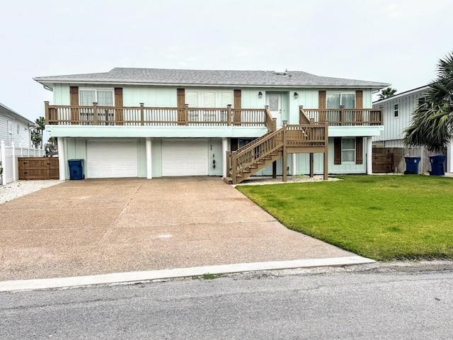 coastal inspired home with stairway, concrete driveway, an attached garage, and a wooden deck