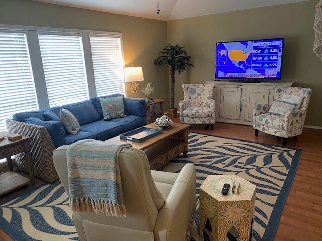 living area with lofted ceiling, wood finished floors, and wooden walls
