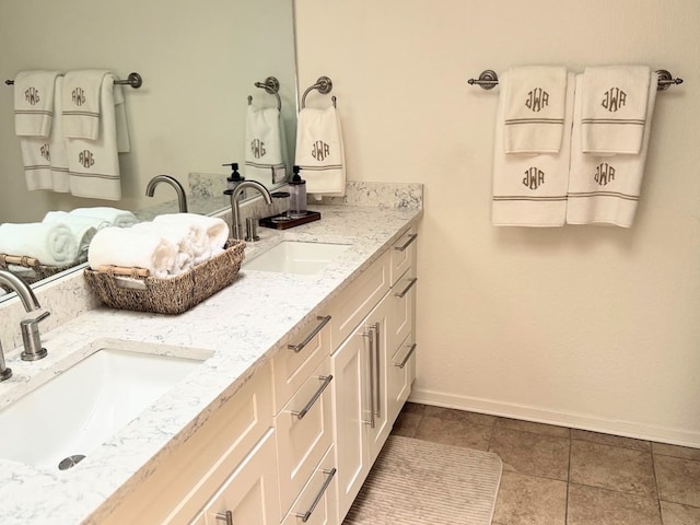 bathroom with baseboards, double vanity, and tile patterned floors