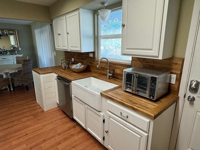 kitchen with butcher block countertops, light wood-style floors, white cabinets, backsplash, and dishwasher