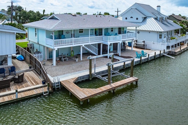 dock area with stairs, a deck with water view, a patio area, and fence