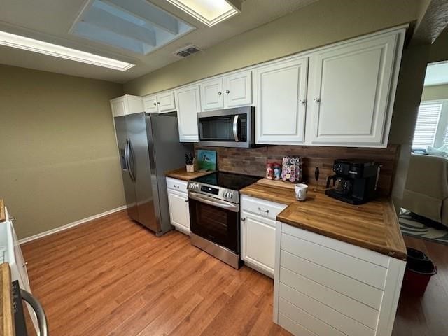 kitchen with stainless steel appliances, white cabinets, wood counters, and light wood finished floors