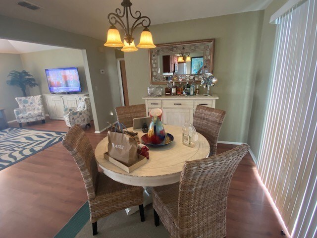 dining area featuring dark wood-type flooring, a chandelier, and baseboards
