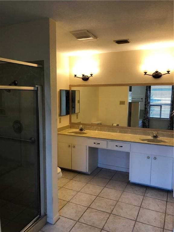 bathroom featuring toilet, tile patterned flooring, a shower with shower door, and vanity