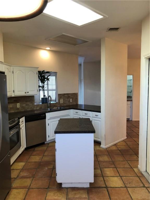 kitchen featuring white cabinets, a kitchen island, appliances with stainless steel finishes, and sink