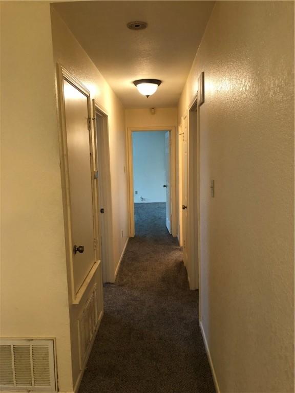 corridor featuring dark carpet