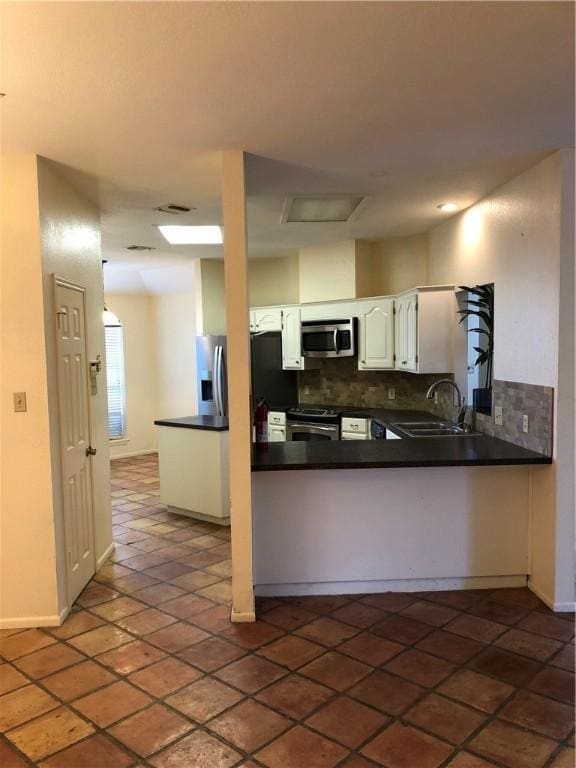 kitchen featuring white cabinets, stainless steel appliances, sink, backsplash, and kitchen peninsula