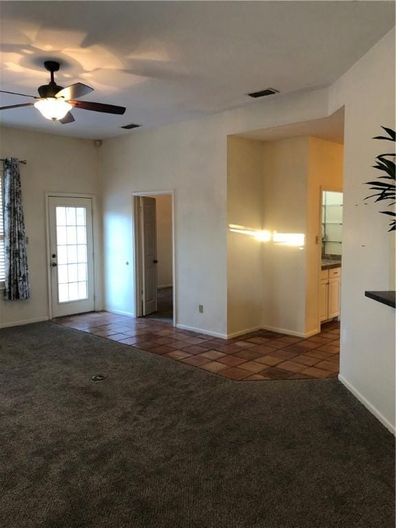 spare room featuring ceiling fan and dark tile patterned floors