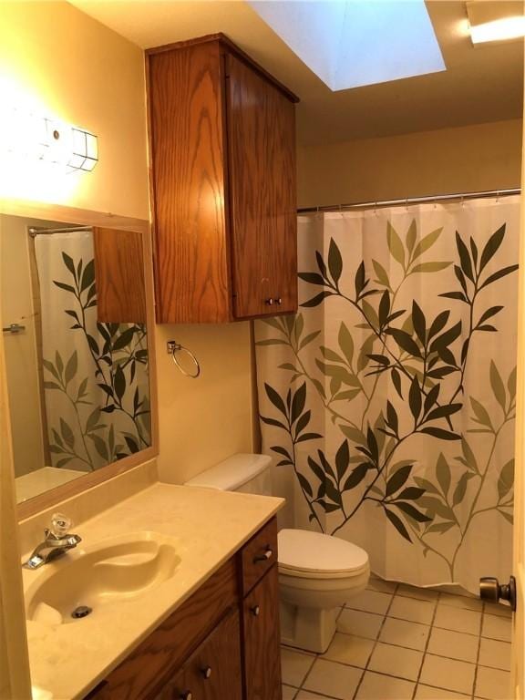 bathroom featuring toilet, tile patterned flooring, a skylight, and vanity