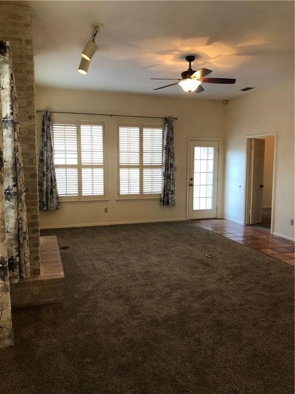 unfurnished living room featuring ceiling fan and dark tile patterned floors