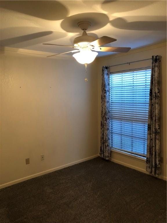 spare room featuring ceiling fan and dark colored carpet