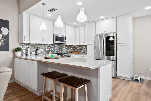 109 Starlight, Ingleside, TX 78362 - kitchen featuring appliances with stainless steel finishes, a breakfast bar, visible vents, a peninsula, and light wood-type flooring