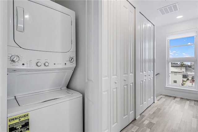 laundry room featuring light hardwood / wood-style floors and stacked washer / drying machine