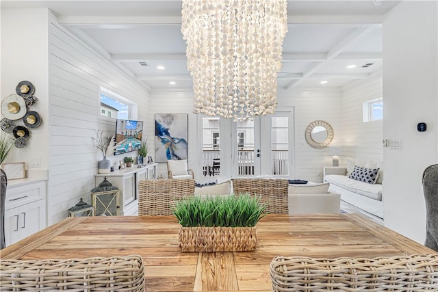 dining room with french doors, coffered ceiling, beamed ceiling, a notable chandelier, and wood walls