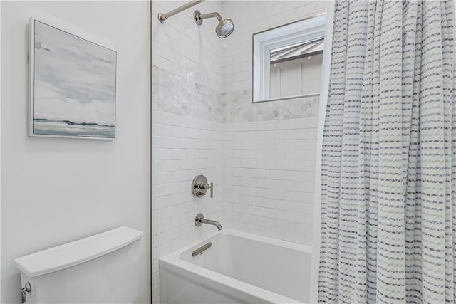 bathroom with tiled shower / bath combo and toilet