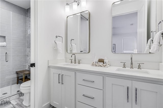 bathroom featuring vanity, a shower with shower door, and toilet