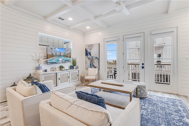 living room with beam ceiling, wooden walls, light hardwood / wood-style floors, and coffered ceiling