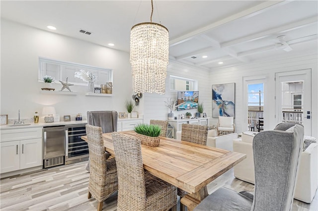 dining area with beam ceiling, coffered ceiling, wine cooler, a notable chandelier, and light hardwood / wood-style floors