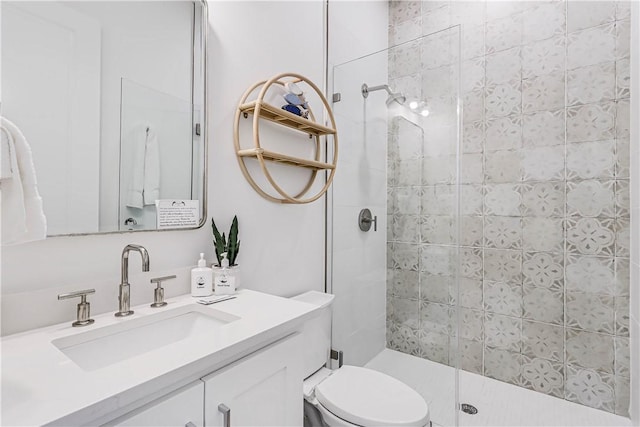 bathroom featuring tiled shower, vanity, and toilet